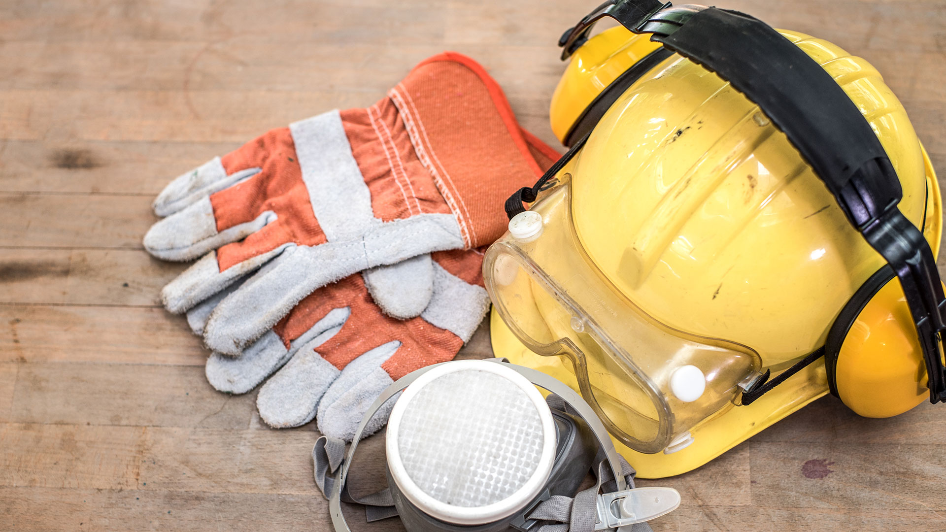 yellow construction helmet, breathing mask, pair of gloves on table